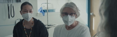 two women sitting together wearing medical masks